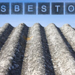 "Asbestos" written in block letters above a degrading metal roof